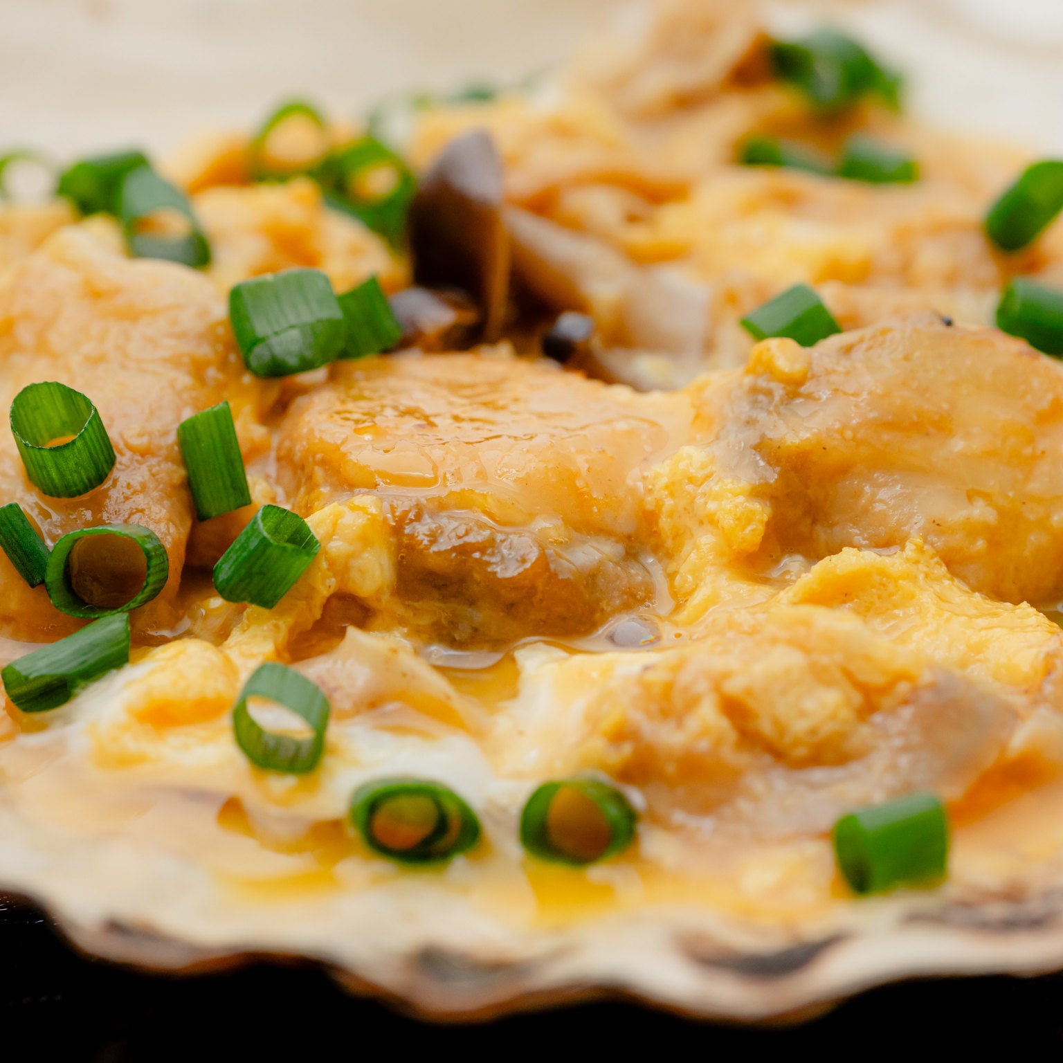 ほたて貝焼きみその素の調理イメージで、半熟の玉子がほたてにとろりと絡んでいます。